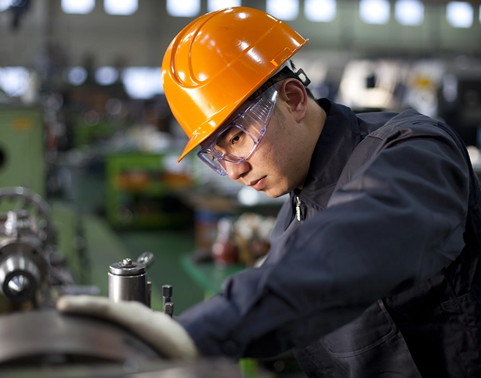 A picture of afactory male worker adjusting machines.