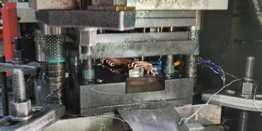 An industrial machine pressing metal components, showing detailed mechanical parts and wiring.