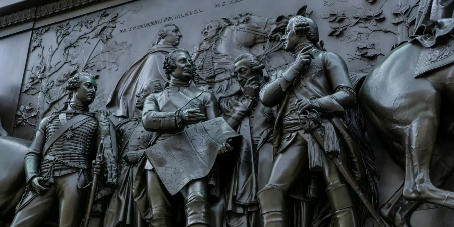A detailed bronze sculpture depicting an equestrian war monument, featuring a mounted soldier or general in uniform, holding a sword, with a relief of a battle strategy map and a group in discussion. The artwork showcases craftsmanship, historical heritage, and military pride on a public outdoor display.