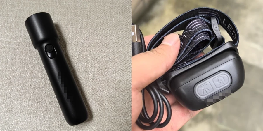 A black handheld flashlight with a button, placed on fabric, and a black LED headlamp with a strap and buttons, held in hand.