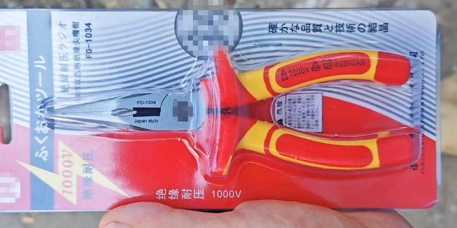 A pair of red and yellow insulated needle-nose pliers with a 1000V rating, packaged on a card with Japanese text.
