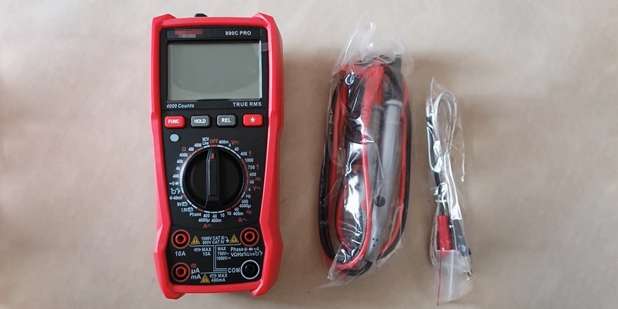 A red digital multimeter with a display screen and multiple buttons, accompanied by packaged test leads and probes.