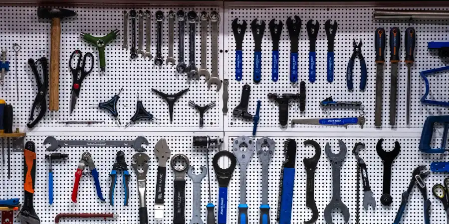A neatly organized pegboard displaying a variety of hand tools, including hammers, wrenches, pliers, and screwdrivers, arranged in rows.
