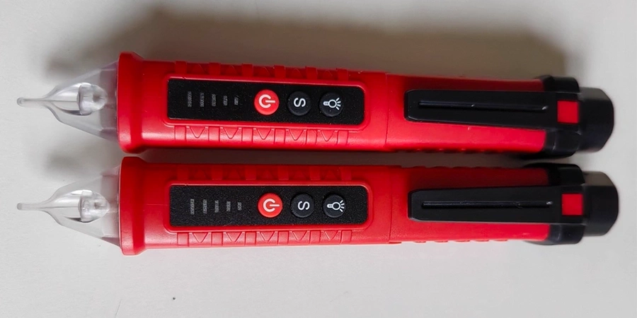 Two red handheld voltage testers with buttons and a clear tip, placed side by side.
