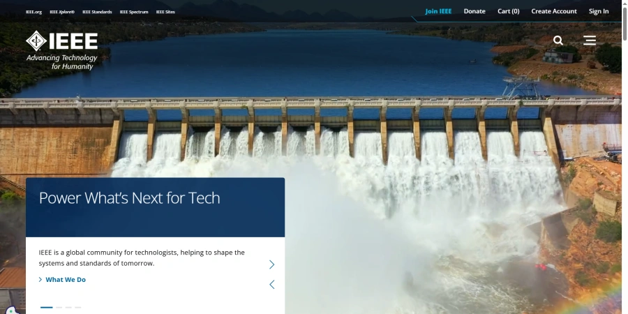 A screenshot of the IEEE website homepage with a background image of a large dam spilling water over its gates into a blue reservoir, surrounded by rocky terrain. The IEEE logo in blue and white says 