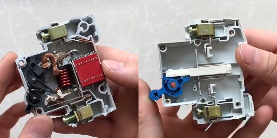 A side-by-side image showing the internal components of a Miniature Circuit Breaker (MCB) and an isolating switch. On the left, the MCB reveals a complex interior with a red circuit board, copper coils, and metal contacts, held in a hand. On the right, the isolating switch displays a simpler design with a blue lever mechanism and minimal internal parts, also held in a hand. The background is a plain light-colored surface.