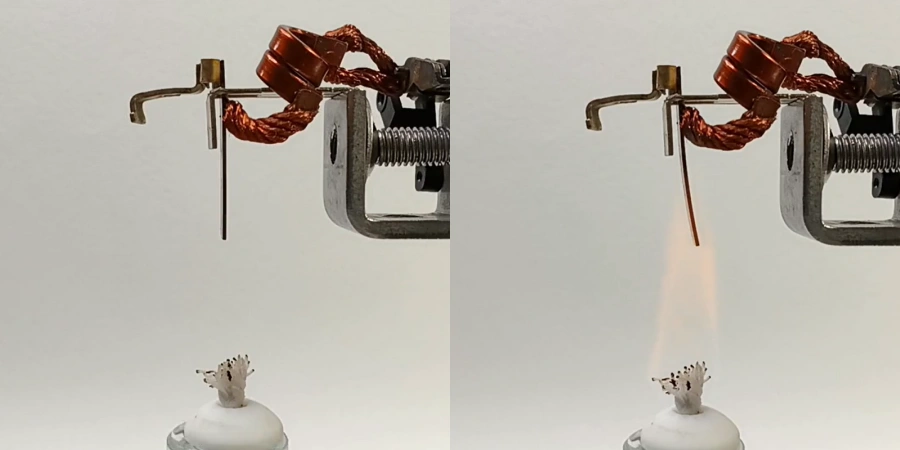 Two side-by-side images showing a bimetallic strip experiment: the left image depicts a metallic strip with a copper coil attached, suspended above a white candle wick on a base; the right image shows the same setup with the strip bending upward as a small flame from the wick heats it. The strip is mounted on a metal clamp with a screw mechanism, demonstrating thermal expansion and bending properties.