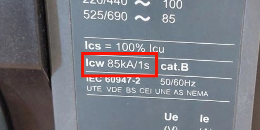 A close-up photograph of a circuit breaker label with technical specifications. The label, highlighted with a red box around the key detail 'Icw 85kA/1s,' indicates the rated short-time withstand current of 85 kiloamperes for 1 second. Additional details include voltage ratings (220/440V and 525/690V), frequency (50/60Hz), and compliance with standards such as IEC 60947-2, UTE, VDE, BS, CEI, UNE, and NEMA. The background shows part of the circuit breaker device, emphasizing its industrial design.