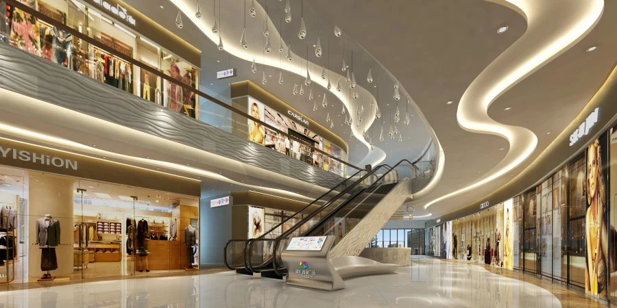 A spacious and modern shopping mall interior with multiple levels, featuring escalators connecting the floors. The design includes sleek storefronts with prominent brand names like "YISHION" and "CAMPARI," adorned with mannequins displaying fashionable clothing. The ceiling is decorated with elegant hanging light fixtures and flowing wave-like light strips, while the polished marble floor reflects the bright, ambient lighting.