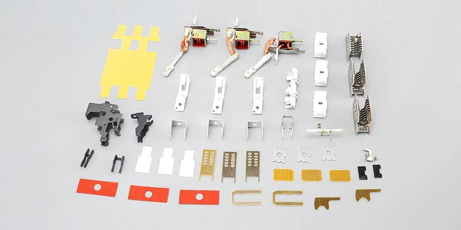 A set of 40/63 Amp 25kA MCCB SKD kit components arranged on a gray surface, including yellow and white plastic parts, black connectors, metal clips, switches with wires, and red and gold-colored pieces, designed for assembling or repairing molded case circuit breakers.