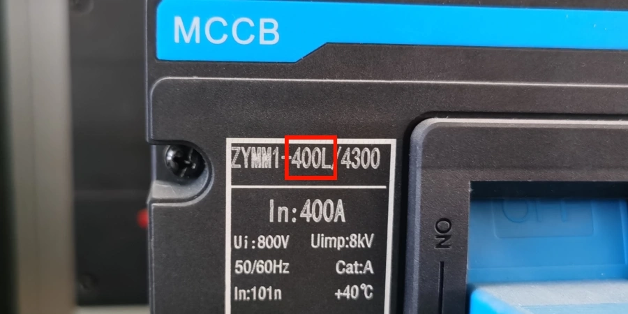 A close-up view of a mccb label with the model number ZYMM1-400L/4300 highlighted in red. The label lists specifications including 400A current, 800V voltage, 50/60Hz frequency, Category A, and +40°C temperature, set against a black and blue device background.