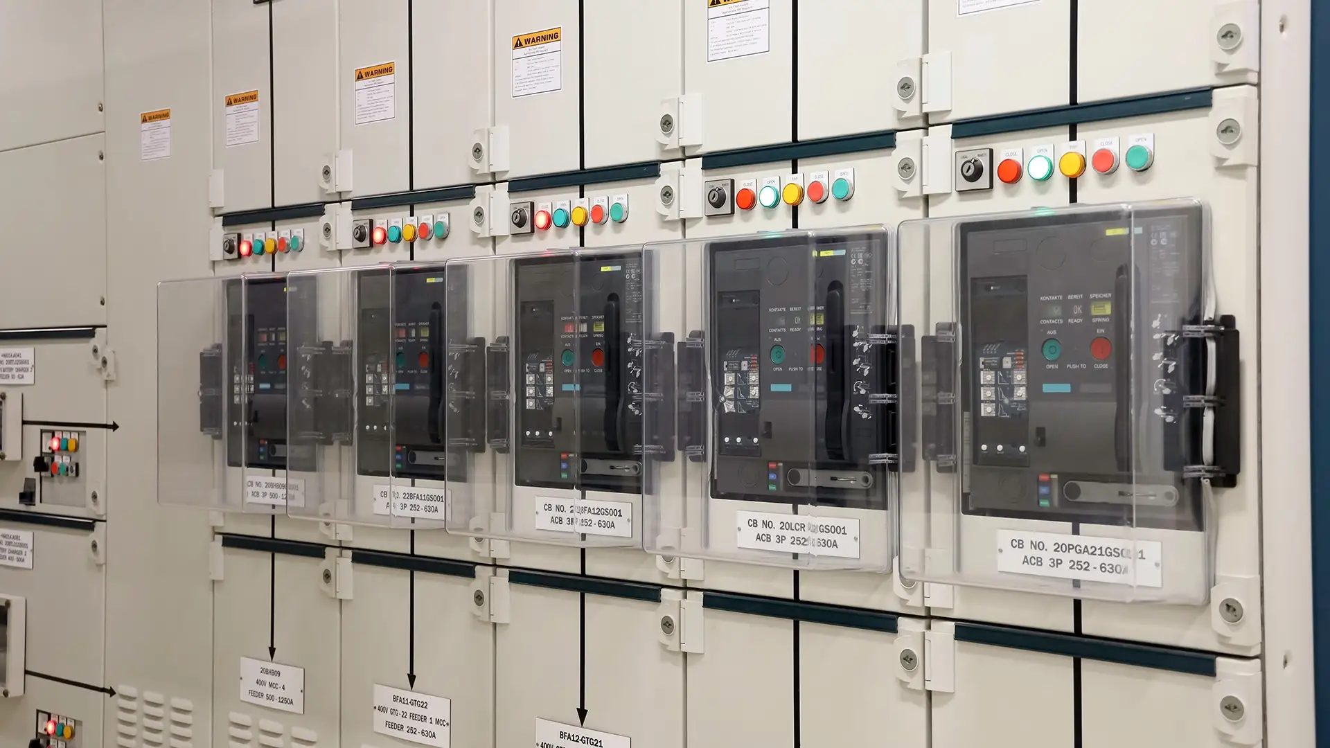 A row of five three-pole air circuit breakers (ACBs) with transparent protective covers mounted inside a low-voltage switchgear cabinet. Units range from 500A to 630A, featuring digital displays, status indicators, open/close buttons, and clear labeling for industrial power distribution.