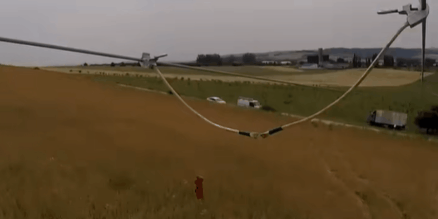 A bright green-white arc flash erupts between two power lines during a phase-to-phase short-circuit test in a rural field, with poles and a building in the background.