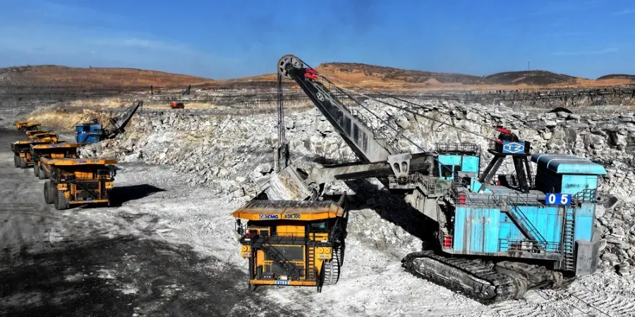 Wide view of a massive open-pit mine showing a huge blue rope shovel excavator loading=