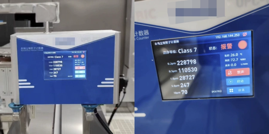 A blue laser particle counter device with digital display showing real-time airborne particle counts in a cleanroom environment. The screen indicates Class 7 status with particle sizes=