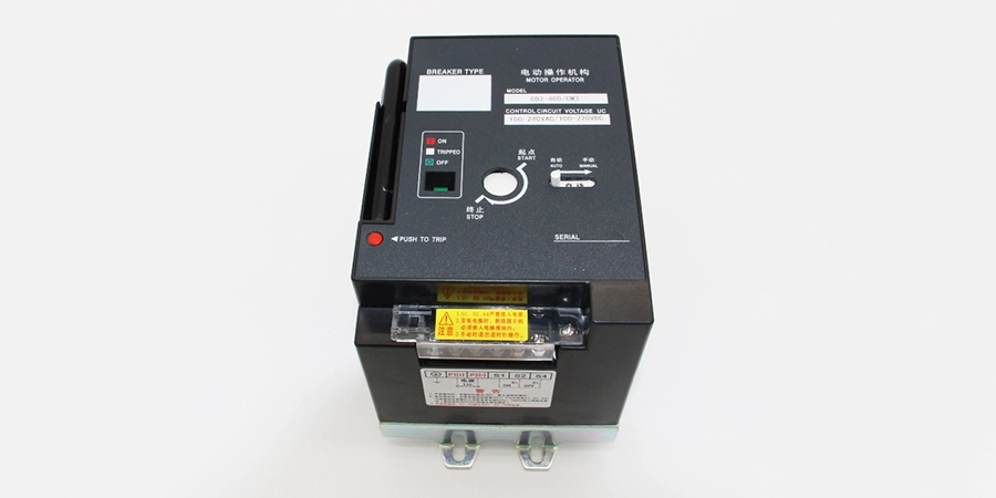 A black motorized operating mechanism designed for MCCBs, featuring ON (green), TRIPPED (red), and OFF buttons, a manual operating handle on the left, a rotary test knob, and a yellow caution label. The front panel displays control voltage rating and serial number.