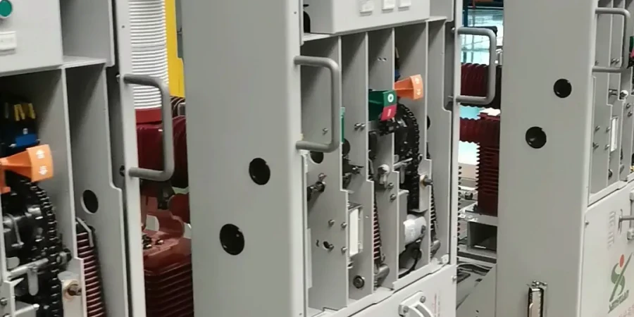 Open railway switchgear cabinets showing indoor high-voltage vacuum circuit breakers designed for rail transport applications. The center unit displays the breaker mechanism with red and green operating handles, copper busbars, current transformers, insulators, and grounding switch. Adjacent cabinets contain similar railway-grade circuit breaker equipment.