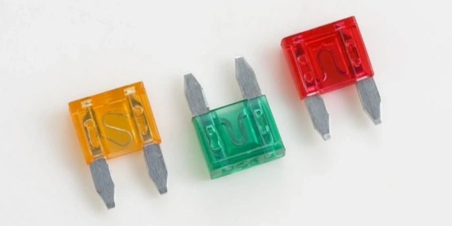 Three automotive blade fuses on a white background. From left to right. Each has two metal prongs for plugging into a fuse box.