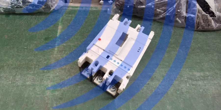 A white three-pole mccb on a green workbench, showing potential EMI interference indicated by blue wave patterns in the background, with visible connection terminals, transparent window, and indicator buttons