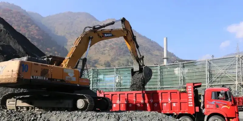 A bright yellow tracked excavator digging and loading=