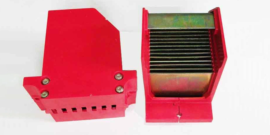 Two views of a red plastic arc chute unit from an air circuit breaker. On the left is the closed exterior side showing a slanted red housing with mounting holes at the bottom secured by two bolts, ventilation slots along the base, and a sturdy rectangular shape. On the right is the open interior view revealing a stack of multiple thin parallel metal plates (arc splitters), mounted inside the red insulating frame to extinguish electrical arcs during circuit interruption.