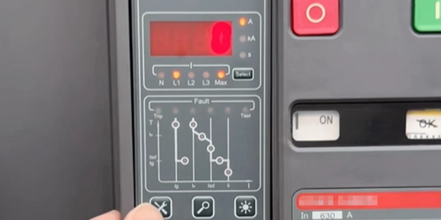 Close-up of an industrial air circuit breaker control panel. The panel features a red digital display, multiple indicator lights for L1, L2, L3, and Max phases, a fault characteristic graph, and physical buttons including a red stop button and an ON status indicator.