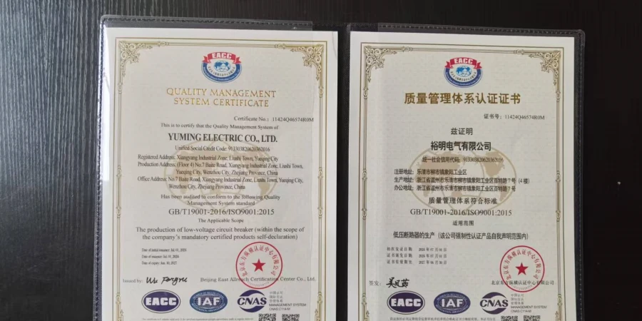 An ISO 9001:2015 Quality Management System Certificate issued to Yuming Electric Co., Ltd. for the production of low-voltage circuit breakers. The document is displayed in two versions, one in English and one in Chinese, side-by-side in a black folder. Both pages feature official gold borders, the EACC logo at the top, and various certification stamps including IAF and CNAS at the bottom.