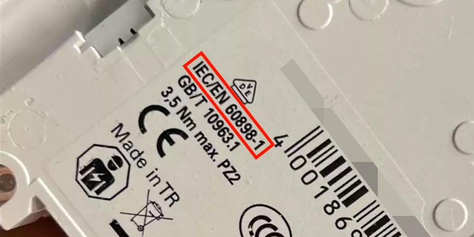Close-up of the white plastic body of an electrical miniature circuit breaker (MCB) with printed label details, highlighting 'IEC/EN 60898-1' in a red box along with related standards 'GB/T 10963.1', torque specification '3,5 Nm max.', CE marking, CCC symbol, 'Made in TR' (Turkey), barcode, and various certification icons including a triangle warning symbol and crossed-out wheelie bin for disposal, typical safety and compliance information found on the side or bottom of residential or commercial circuit protection devices.