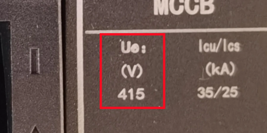 A close-up view of a molded case circuit breaker (MCCB) nameplate/label on a dark gray or brown device body. The highlighted section shows markings: 'Ue:' followed by '415' in the column labeled '(V)' for voltage, indicating the rated operational voltage of 415 volts.