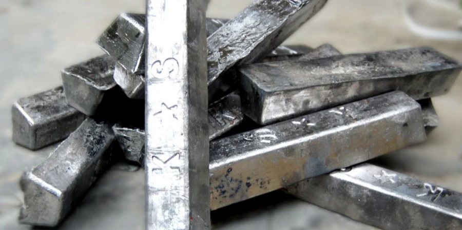 Pile of stamped lead ingots stacked irregularly on a concrete surface