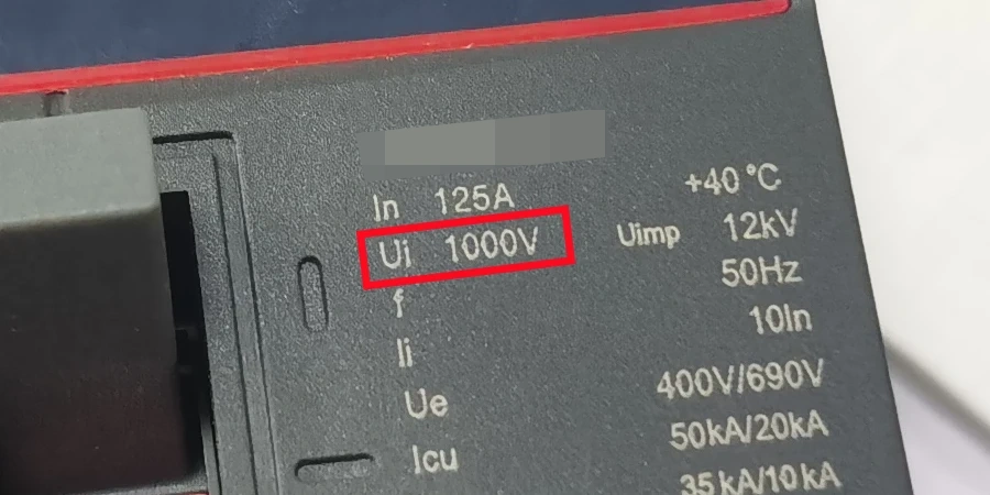 Close-up view of a black MCCB label with white text, featuring a red rectangular highlight around 'Ui 1000V', along with specifications including In 125A, Uimp 12kV, 50Hz, +40 °C, and other technical ratings