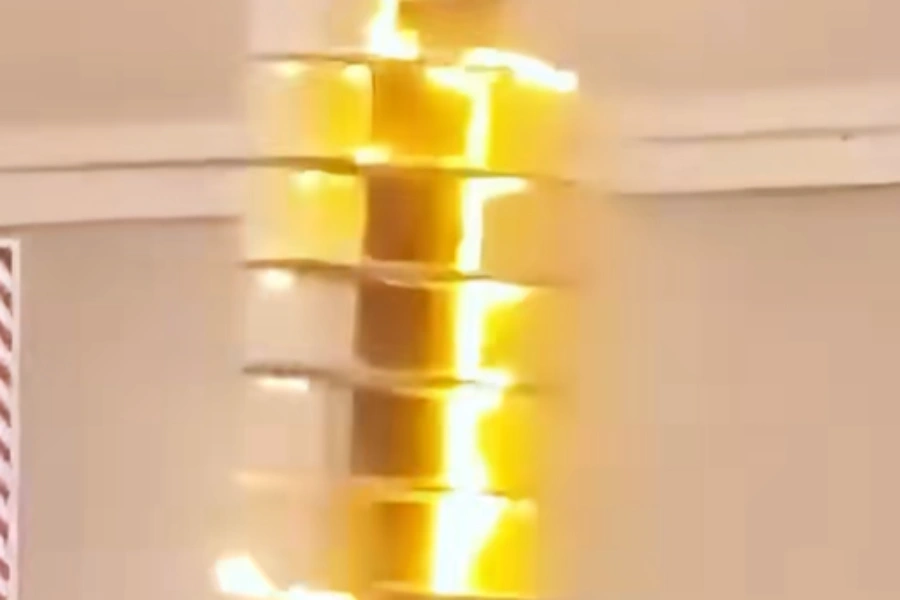 Bright yellow electrical arcs and glowing discharge during a flashover test on a cylindrical insulator, viewed from below with visible glowing rings and intense light